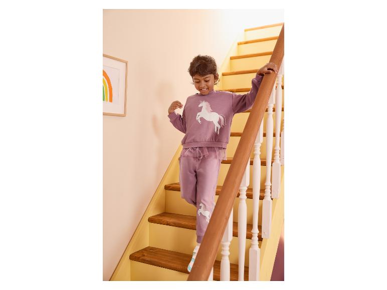 Mädchen in lila Einhorn-Trainingsanzug geht die Treppe hinunter.