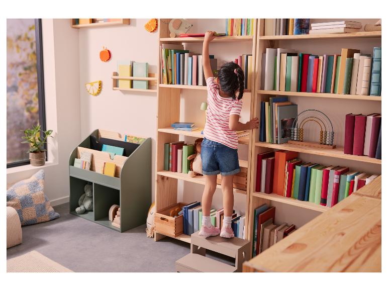 Holzbücherschrank, grünes Bücherregal, Mädchen sortiert Bücher ein.