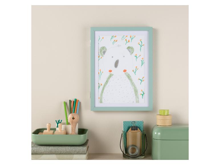 Ein mintgrüner Bilderrahmen mit einer Zeichnung eines Koalas und grüne Bleistifte in einem mintgrünen Halter.