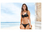 Eine Frau trägt einen schwarzen Bikini am Strand.