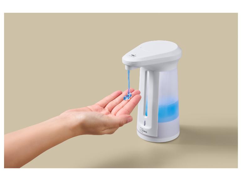 Eine Hand erhält Seife aus einem automatischen Spender mit blauer Flüssigkeit.