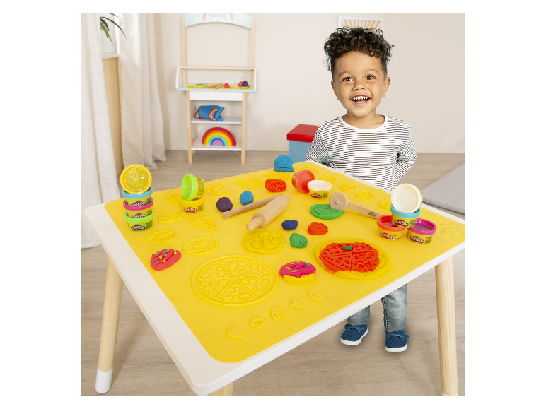 Ein Kind spielt mit Play-Doh Knete an einem Tisch mit einer speziellen Matte.