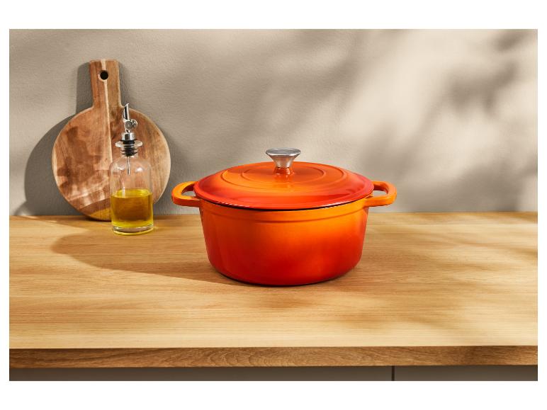 Orangener Le Creuset Topf aus Gusseisen auf einer Holztheke.