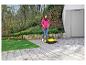 Frau kehrt Terrasse mit Kehrmaschine, Kinderfahrrad und Ball im Hintergrund.