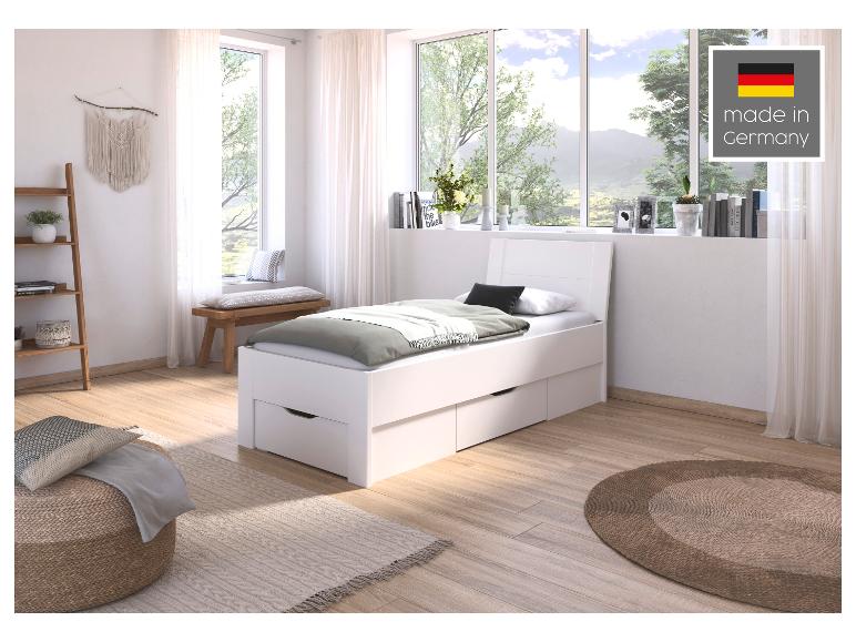 Weißes Bett mit Schubladen in einem hellen Schlafzimmer mit Naturblick, „Made in Germany“.