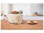 Cremefarbener Toaster mit zwei Scheiben dunklem Brot und einem Teller mit Tomatenbrot.