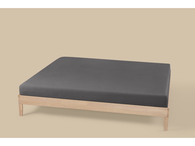 Ein Holzlattenrost mit einem dunkelgrauen Spannbettlaken auf hellbeigem Hintergrund.