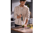 Mann in der Küche bereitet Pesto mit einem Stabmixer zu.