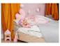 Baby Born Puppe im rosa Schlafanzug schläft in einem Kinderbett mit Spielzeug.