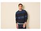 Mann in einem marineblauen und blau gestreiften Strickpullover und dunklen Jeans.