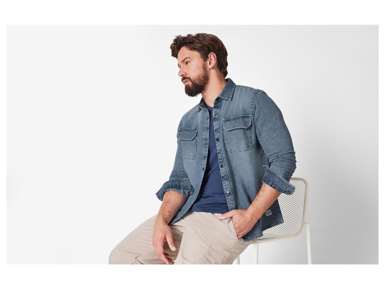Mann trägt ein Jeanshemd und beige Hose.
