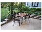 Garten-Essgruppe aus Holz und Metall mit vier Stühlen auf einer Terrasse.