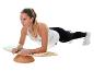 Frau macht Plank auf einem Balance Board, in Sportkleidung.