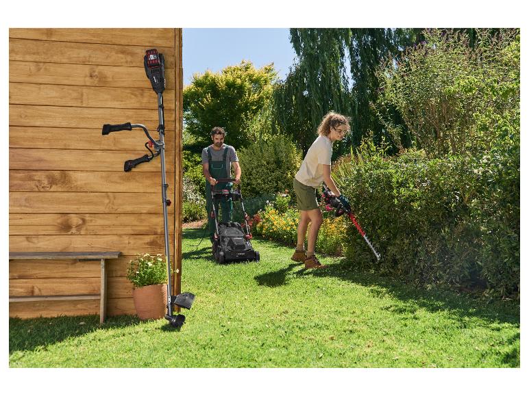 Mann mäht den Rasen mit einem Rasenmäher und Frau schneidet die Hecke mit einer Heckenschere im Garten.