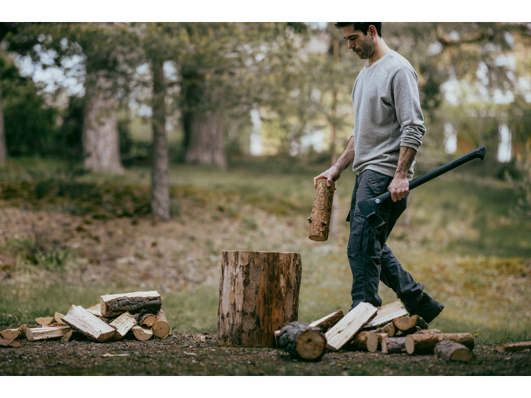 Mann mit Axt und Holzscheit, bereit zum Holzhacken im Freien.