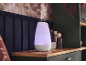 Ein farbwechselnder Aroma-Diffusor, der Nebel auf einem Holzregal in einem gemütlichen Raum abgibt.