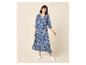 Frau in einem blau-weiß gemusterten Maxikleid mit 3/4-Ärmeln und weißen Turnschuhen.