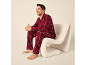 Mann im rot karierten Pyjama sitzt auf einem modernen weißen Sessel.