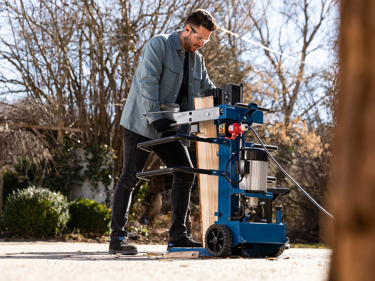 Ein Mann verwendet einen elektrischen Holzspalter, um Holz zu spalten.