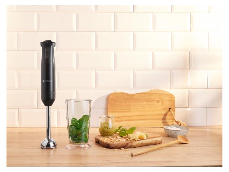 Stabmixer mit Pesto-Zutaten auf einer Holz-Arbeitsplatte.