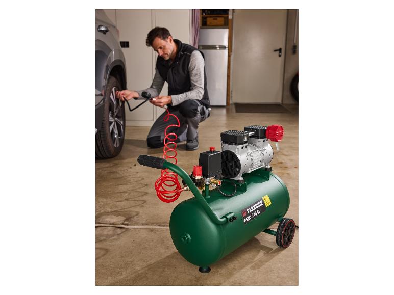 Ein Mann benutzt einen Parkside Luftkompressor, um einen Autoreifen in einer Garage aufzupumpen.