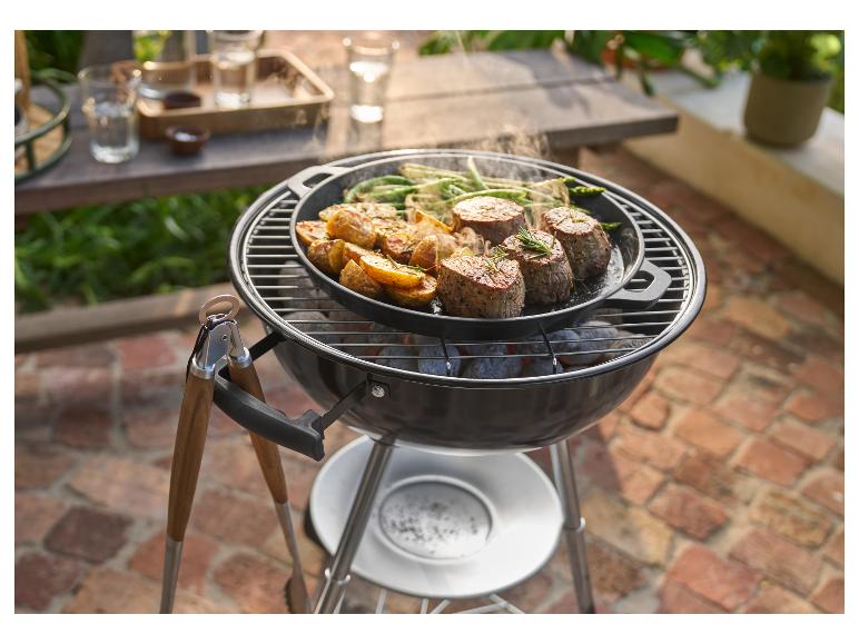 Grill mit Pfanne voller gegrilltem Fleisch, Kartoffeln und grünen Bohnen, mit Zange daneben.