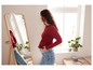 Eine schwangere Frau in einem roten Oberteil und blauen Jeans schaut in einen Spiegel.