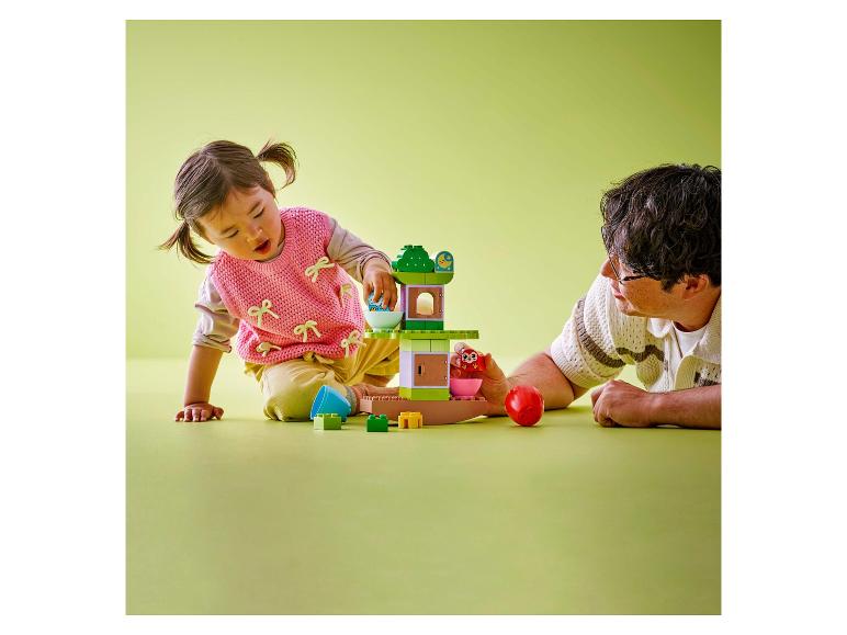 Kind und Erwachsener spielen mit einem LEGO DUPLO Baumhaus.