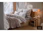Gemütliches Schlafzimmer mit winterlicher Bettwäsche, Decke und Holz-Nachttisch.