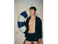 Mann in schwarzen Boxershorts und offener Jacke hält einen Schwimmreifen.