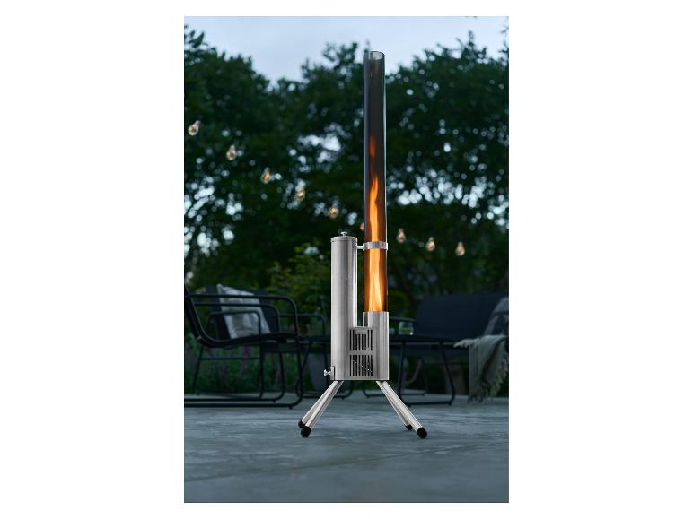 Terrassenheizer mit Flamme in Glasröhre, in einem Garten mit Lichterketten.