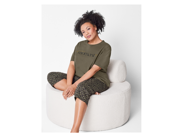 Eine Frau trägt ein olivgrünes Shirt und eine Hose mit Leopardenmuster.