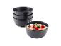 Set schwarzer Schalen, eine davon gefüllt mit Haferflocken, Beeren und Minze.