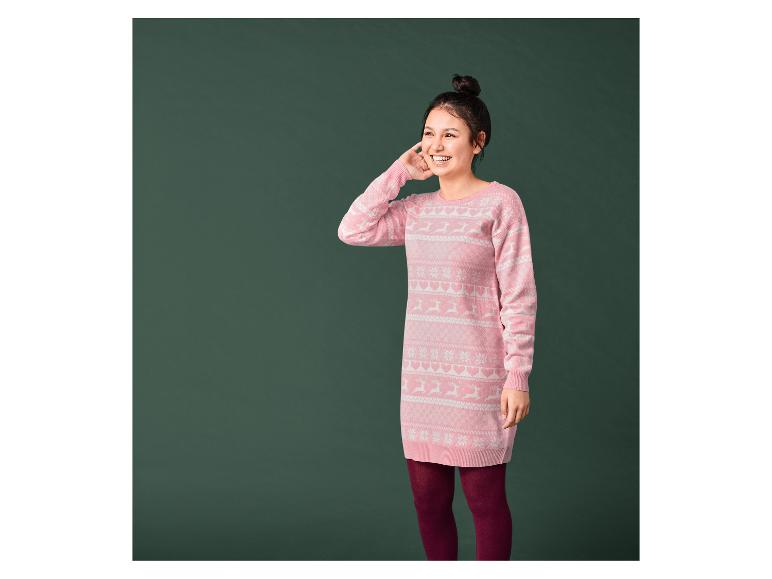 Eine Frau in einem rosa Weihnachtspullover mit Rentieren und Schneeflocken.