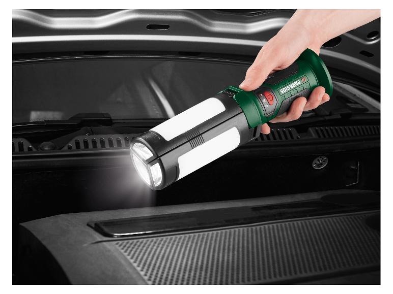 Eine Hand hält eine ausklappbare Taschenlampe, die den Motorraum eines Autos beleuchtet.