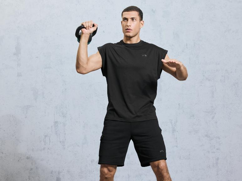 Ein Mann in schwarzem T-Shirt und Shorts trainiert mit einer Kettlebell.