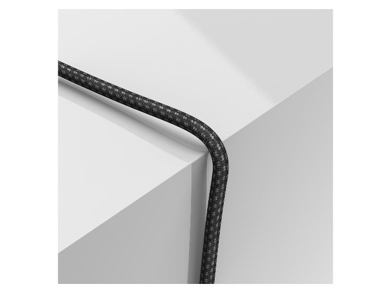 Ein schwarzes geflochtenes Kabel, das über eine weiße geometrische Oberfläche drapiert ist.