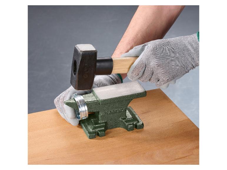 Person benutzt Hammer und Amboss, um an einer Metallklemme zu arbeiten.