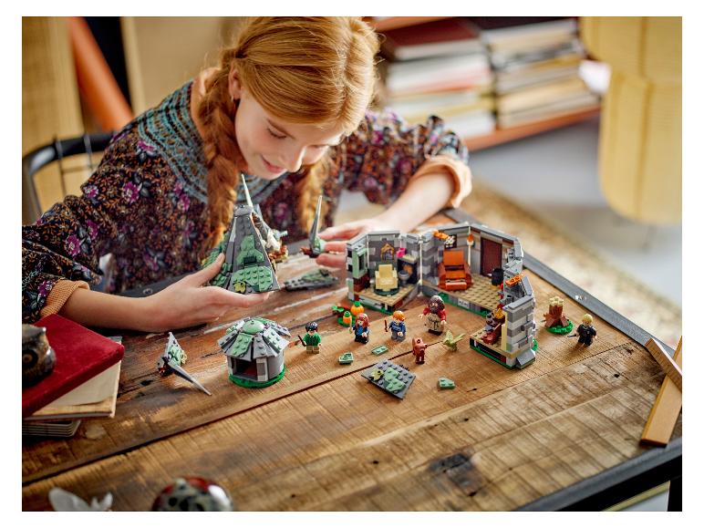 Ein Mädchen spielt mit LEGO Harry Potter Sets auf einem Holztisch.