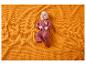 Baby in rotem Strampler auf einer orangefarbenen Decke liegend.