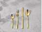 Goldfarbenes, vierteiliges Besteckset auf grauem Hintergrund.
