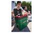Zwei Männer im Freien, einer öffnet eine grün-schwarze Kühlbox mit Obst darin.