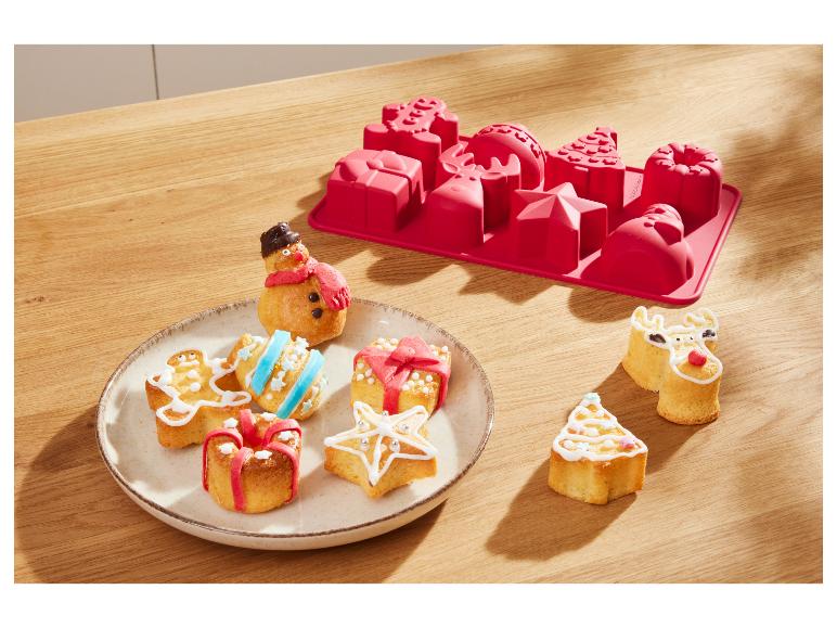 Festliche Weihnachtskuchen und eine rote Silikonbackform auf einem Holztisch.