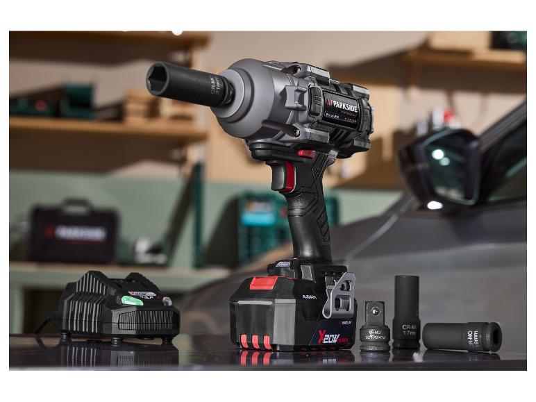 Schlagschrauber mit Akku, Ladegerät und Nüssen, mit einem Auto im Hintergrund.