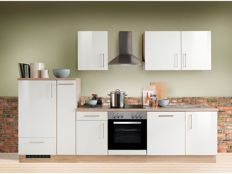 Weiße Küche mit Backofen, Spüle und Oberschränken.