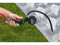 Hand hält eine Aufblaspistole mit Manometer, die eine transparente Luftmatratze auf Gras aufbläst.