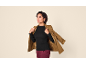 Frau in schwarzem Langarmshirt, bordeauxroter Hose und braunem Blazer