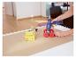 Frau benutzt LIVARNO® Heißklebepistole, um Holzspielzeug auf braunem Papier zu kleben.