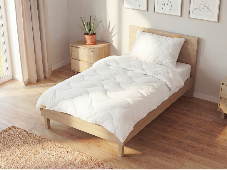 Weiße gesteppte Bettdecke und Kissen auf einem Holzbett in einem hellen Schlafzimmer.