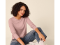 Frau in einem rosa Langarmshirt und blauen Jeans, auf dem Boden sitzend.